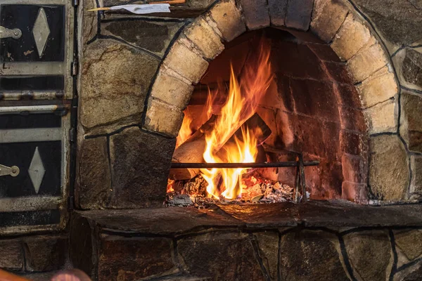 火焰熊熊燃烧的拱形壁炉 照片上有一个漂亮的传统石制壁炉 上面有木柴 还有一个登广告的地方 或在黑暗的背景上写着问候信的地方 — 图库照片