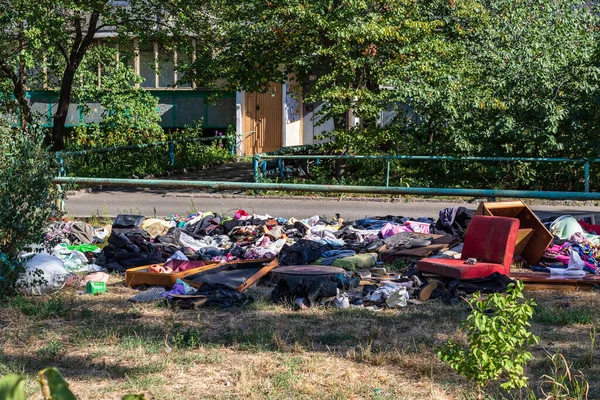 Çevre kirliliği. Büyük bir şehirde, çok katlı bir binanın yakınındaki çimlerin üzerindeki çöplük doğayı çöplerle kirletiyor. Doğa koruma, dikkat. Ekoloji.