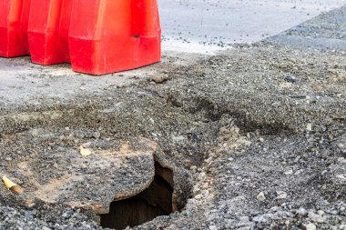 Kırık gri dökme demir rögar kapağı asfalt bir yolda bulunuyor. Araçlar için tehlike.