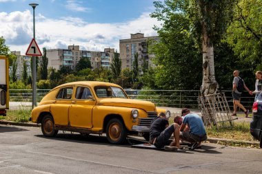 Kyiv, Ukrayna - 13 Ağustos 2020: Retro car GAZ M20 Pobeda şehir caddesinde. 1946 'dan 1958' e kadar Sovyetler Birliği 'nde üretilen eski sarı ve paslı araba. Adamlar başka bir araba arızası üzerinde çalışıyorlar..