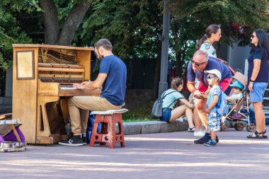 Kyiv Ukrayna - 27 Temmuz 2019: Kimliği belirsiz müzisyen Kyiv 'in merkezindeki Mikhailovskaya Meydanı' nda bir piyanoda çalıyor. Sokak kültürü. Açık havada. Yakın plan..
