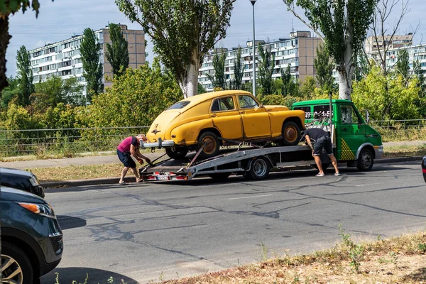 Kyiv, Ukrayna - 13 Ağustos 2020: Retro araba GAZ M20 Pobeda bir şehir caddesinde bir çekiciye yüklendi. 1946 'dan 1958' e kadar Sovyetler Birliği 'nde üretilen eski sarı ve paslı araba..