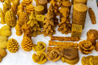 A close up view of hand sculpted wax candles on a stall during a local craft fair. Yellow natural wax. Various forms of products. clipart
