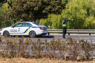 Kyiv Ukrayna - 23 Eylül 2020: Tıbbi maske takan bir polis koronavirüs nedeniyle karantina sırasında otoyolu kontrol etmek için bir aracı durdurdu. Dünya çapında koronavirüs salgını.