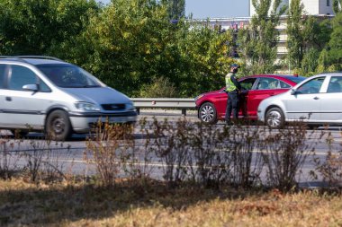 Kyiv Ukrayna - 23 Eylül 2020: Sağlık maskesi takan bir polis memuru, koronavirüs nedeniyle karantina sırasında yoğun bir otoyolda bir arabayı kontrol ediyor. Dünya çapında koronavirüs salgını. Sokak fotoğrafı..