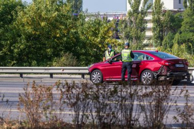 Kyiv Ukrayna - 23 Eylül 2020: Sağlık maskesi takan iki polis koronavirüs nedeniyle karantina sırasında otoyolda bir arabayı kontrol etti. Dünya çapında koronavirüs salgını. Sokak fotoğrafı..