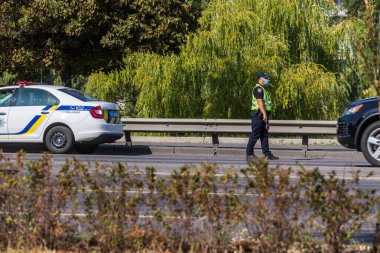 Kyiv Ukrayna - 23 Eylül 2020: Koronavirüs nedeniyle karantina sırasında tıbbi maske takan bir polis memuru pisti izliyor. Dünya çapında koronavirüs salgını. Sokak fotoğrafı..