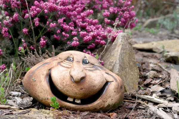 Statue en céramique, tête souriante, dans le jardin de rochers avec floraison H — Photo