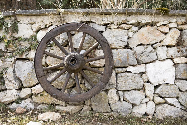 Velha roda de madeira do vagão pendurado contra uma parede de pedra — Fotografia de Stock