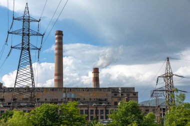 Tüten baca ve elektrik direği, şehrin termik santral arka planı mavi. Borular, tehlike.