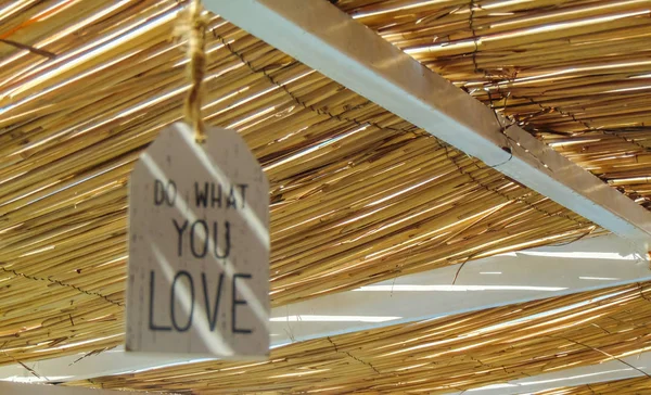 Do what you love inspirational quote hanging on the straw roof .