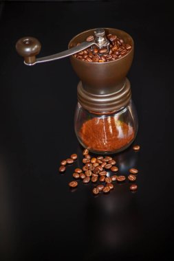 El yapımı kahve öğütücüsü ve siyah arka planda kavrulmuş fasulye..