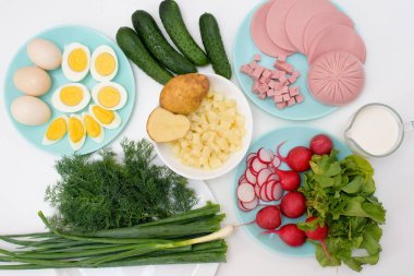 Adım adım Rus soğuk okroshka çorbası tarifi ev yapımı okroshka sosisi, sebze, yumurta, salatalık, patates, turp malzemeleri. Yukarıdan görünüm.