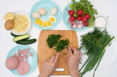 Adım adım Rus soğuk okroshka çorbası tarifi ev yapımı okroshka sosisi, sebze, yumurta, salatalık, patates, turp malzemeleri. Işık arkaplan üzerindeki üst görünüm.