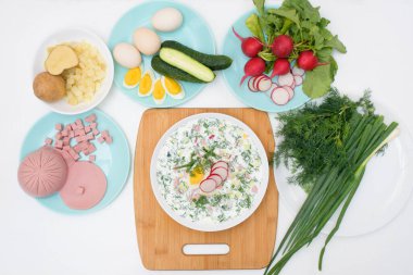 Adım adım Rus soğuk okroshka çorbası tarifi ev yapımı okroshka sosisi, sebze, yumurta, salatalık, patates, turp malzemeleri. Işık arkaplan üzerindeki üst görünüm.