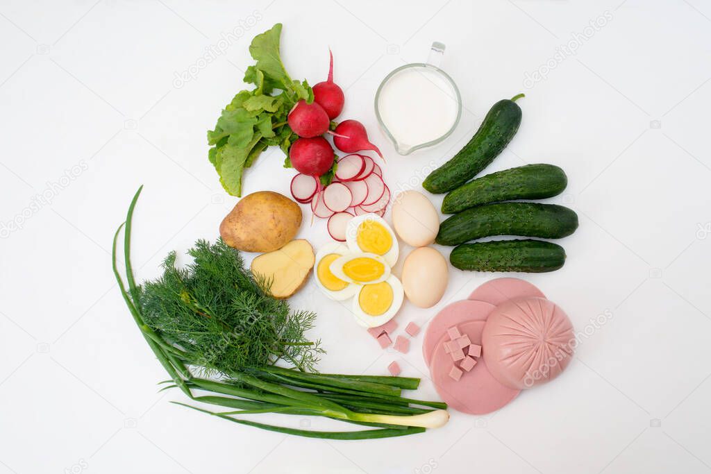 ingredients for a recipe of homemade Russian national cold okroshka soup on a light background. potatoes, radishes, sausage, onions, herbs, eggs. the view from the top.