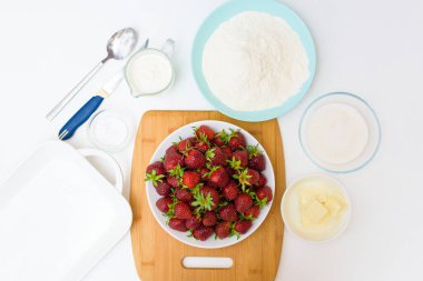 Adım adım çilekli turta olgun taze çileklerden ev yapımı ve hafif arka planda kurabiyeli, üst manzara. Çilekli turta için malzemeler.