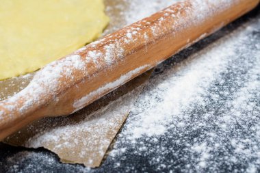 Hamur yerine merdane ve koyu bir arka plana un serpiştirilmiş. Üst görünüm, yakın çekim, metin için boşluk. Evde mangır yapma hazırlığı.