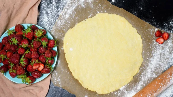 stock image step by step recipe the process of making galetta with strawberries at home, top view on a dark background, ingredients for strawberry pie.