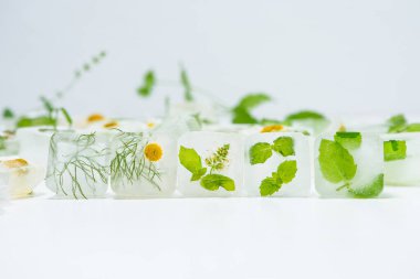 Papatyalı kozmetik buz küpleri ve evde bakım için nane şekeri yüz için kullanılır. Cilt bakımı kavramı. Hafif arka planda bitkilerle kozmetik ürünleri