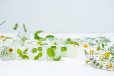 Papatyalı kozmetik buz küpleri ve evde bakım için nane şekeri yüz için kullanılır. Cilt bakımı kavramı. Hafif arka planda bitkilerle kozmetik ürünleri