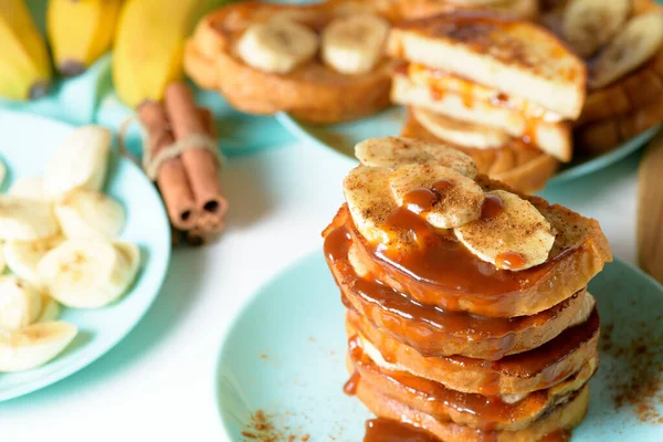 French toast with banana and homemade caramel with cinnamon, Breakfast dessert on a blue plate on a light background.