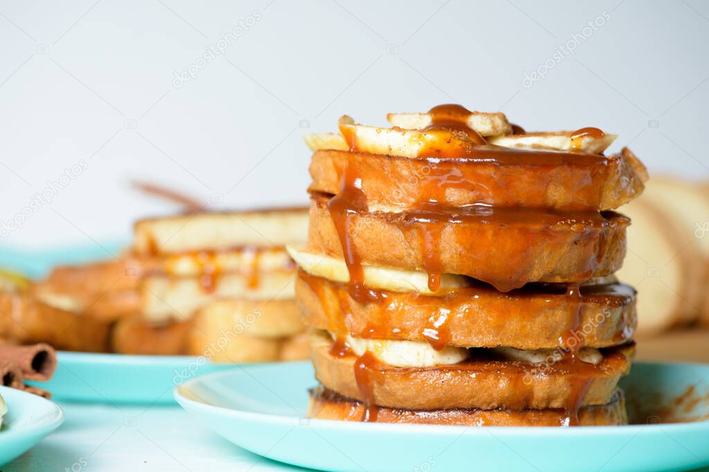 French toast with banana and homemade caramel with cinnamon, Breakfast dessert on a blue plate on a light background.