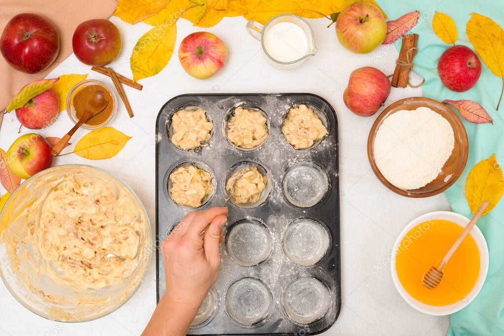 ingredients and recipe for homemade Apple cupcakes and muffins, top view light background, yellow leaves. the concept of fall baking and fall harvest. put the dough with apples in a baking dish.