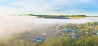 Güneşin doğuşu, sabah erken saatlerde nehir manzarasının üzerindeki sis. Yazın güneş ışınları yoğun sisi aydınlatır..