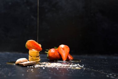 Mini krep gevreği kasesi taze çilekli muz çikolatası, hindistan cevizi talaşı ve küçük tabakta bal. Yukarıdan manzara. Kendini soyutlama eğilimi.