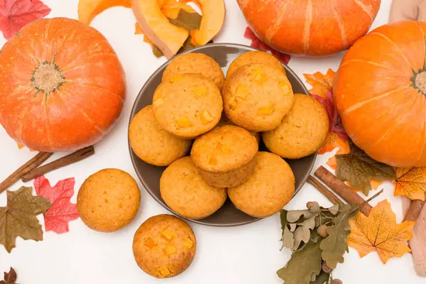 Sonbahar balkabağı kekleri pişirmenin tarifi ve malzemeleri. Işık arkaplanındaki üst görünüm. Ortasındaki bir tabakta balkabaklı taze kekler..