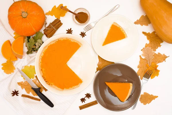 cooking homemade pumpkin pie with spices top view on a light background . autumn dessert of seasonal orange pumpkins. pie cut into pieces on plates.