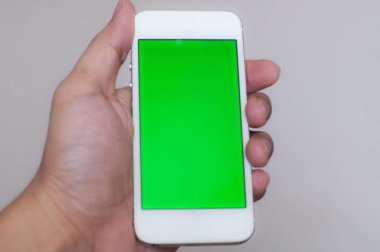 Genç adam bir akıllı telefon ile yeşil perde holding