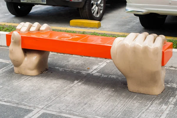 A bench with hands sculpture in the sidewalk