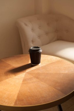 İçerideki ahşap bir masada tek kullanımlık bir kahve.