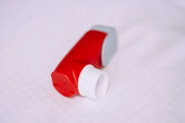 Un bodegón del inhalador de asma rojo y blanco se inventa sobre un fondo blanco — Foto de Stock