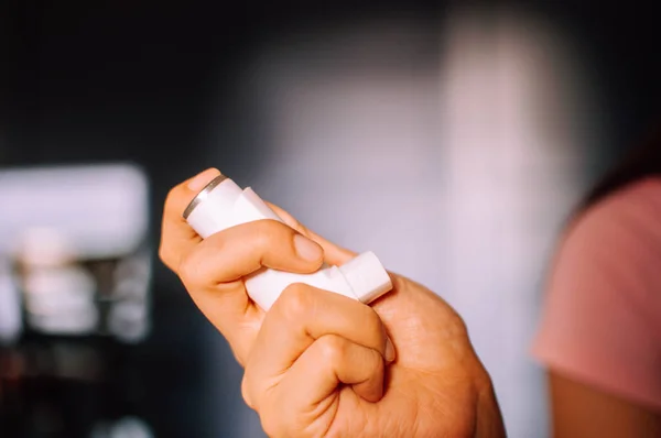 Una mujer joven está usando un dispositivo inhalador de asma en interiores — Foto de Stock