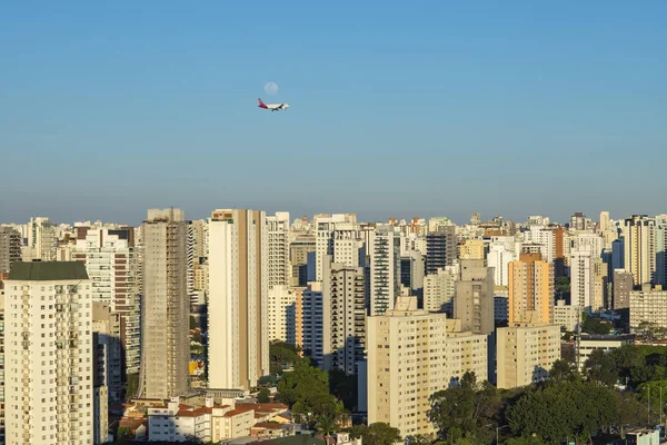 Beautiful landscape in the city, airplane and moon on a sunny day. Sao Paulo city, Brazil.
