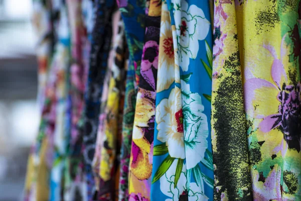 Colorful fabrics hanging and lined. Fabrics with different patterns and colored rows. Wide selection of different color textile.