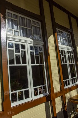 Kahverengi ahşap çerçeveli beyaz pencere. Bu eski geleneksel bir pencere, oyulmuş ahşap kaplamalı, kahverengi çizgileri var.. 