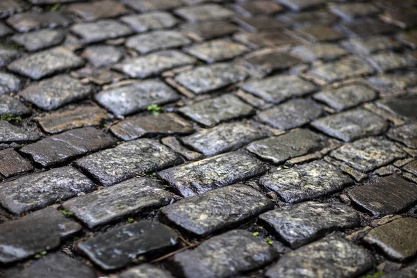 Stone pavement texture. Granite cobblestoned pavement background.  Cobbled stone road regular shapes, abstract background of old cobblestone pavement close-up.