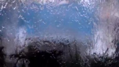 Bulanık arka planda araba cam üzerinde damlama su. 