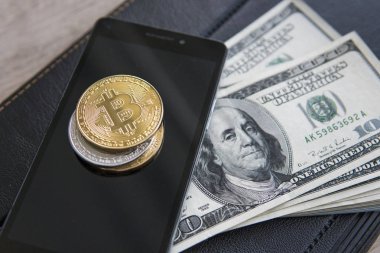 Akıllı telefonda altın bitcoinler ve arka planda dizüstü bilgisayar ile abd doları. Bitcoin kripto currebcy. Dijital para birimi. Kripto para madenciliğinden kar. Ticaretten dolar ile Madenci.