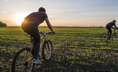 Lutsk, Ukrayna - 5 Nisan 2018: Adam bir bisiklet'nde günbatımı bir sahaya sürmek.
