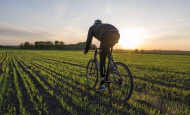 Lutsk, Ukrayna - 5 Nisan 2018: Adam bir bisiklet'nde günbatımı bir sahaya sürmek.
