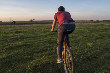 Adam'nde günbatımı Bisiklete binmek. Gün batımında binmek. Sağlıklı yaşam konsepti. Erkek binmek bisiklet güneşte ayarlayın. Motorcu gün batımlarını gökyüzü bir alan üzerinde bisiklete binmek. Spor.