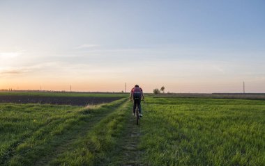 Adam'nde günbatımı Bisiklete binmek. Gün batımında binmek. Sağlıklı yaşam konsepti. Erkek binmek bisiklet güneşte ayarlayın. Motorcu gün batımlarını gökyüzü bir alan üzerinde bisiklete binmek. Spor.