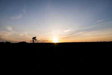 Lutsk, Ukrayna - 5 Nisan 2018: Adam bir bisiklet'nde günbatımı bir sahaya sürmek.