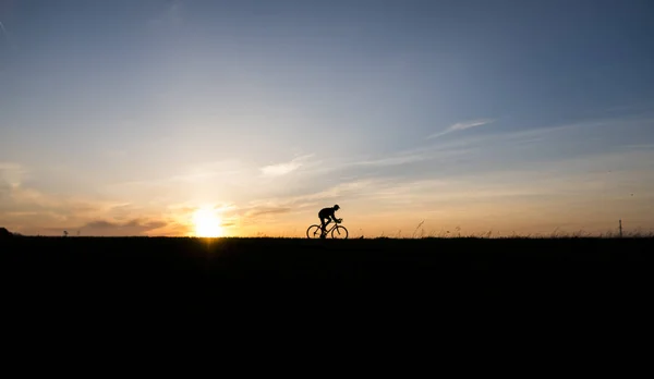 Луцк, Украина - 5 апреля 2018 года: Человек ездит на велосипеде на закате на поле . — стоковое фото