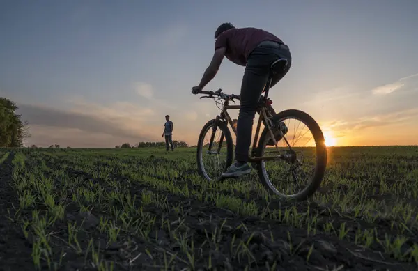 Lutsk, Ucrânia - 5 de abril de 2018: Homem anda de bicicleta ao pôr-do-sol em um campo . — Fotografia de Stock